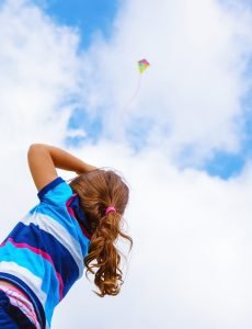 Little girl looking up in the sky on beautiful colorful air kite