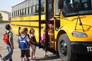 Elementary school students get on school bus